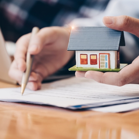 A person holding a pen and house model